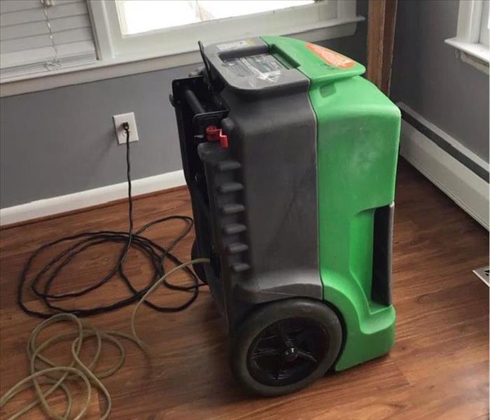 A photo showing a commercial grade dehumidifier drying out a home.